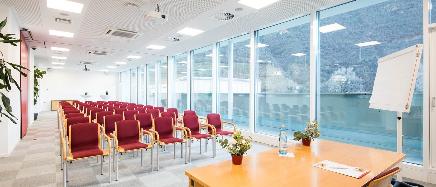 Vermietung Seminarräume Moderner, leerer Konferenzraum mit roten Stühlen und großem Fenster