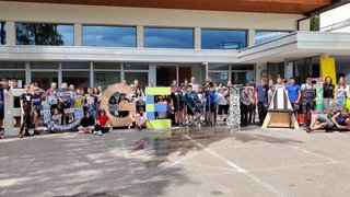 Junghandwerker Große Gruppe von Menschen posiert mit großen Buchstaben vor einem Gebäude