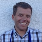 Federkielsticker Lächelnder Mann mit kariertem Hemd und blauem Latzschurz vor weißer Wand