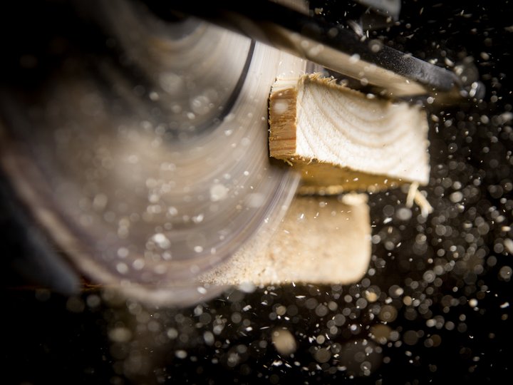 Sägewerker und Verpackungshersteller Drehende Kreissäge schneidet Holz mit Holzspänen im Flug