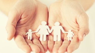 Webinare Hände halten Papierfiguren einer Familie mit zwei Kindern