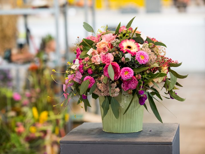 Floristen Bunter Blumenstrauß in grünem Topf auf grauem Podest