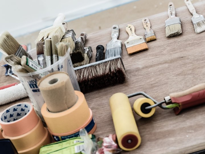 Maler und Lackierer Verschiedene Malerwerkzeuge wie Pinsel, Farbroller und Klebeband auf Holzfläche