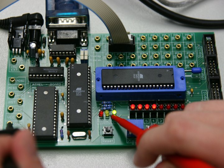 Elektromechaniker Hand hält Messspitze an leuchtende LEDs auf einer grünen Leiterplatte