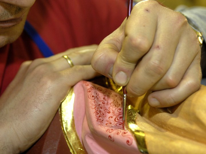 Fassmaler und Vergolder Mann bemalt mit Pinsel detailreiche Muster auf goldenem und rosa Objekt