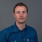 Sägewerker und Verpackungshersteller Porträt eines Mannes mit blauem Hemd vor grauem Hintergrund