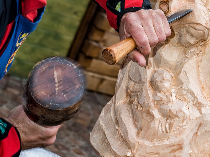 Holzbildhauer Nahaufnahme eines Holzschnitzers, der eine Holzfigur mit Meißel und Hammer bearbeitet
