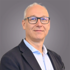 Unfall und Krankheit Porträt eines lächelnden älteren Mannes mit Brille und Anzug vor grauem Hintergrund