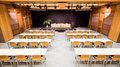Vermietung Seminarräume Konferenzraum mit Stuhlreihen und Bühne mit schwarzen Vorhängen