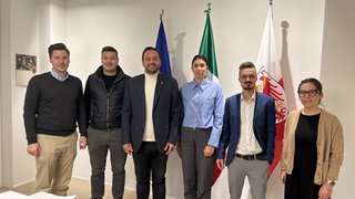 Junghandwerker Sechs Personen stehen nebeneinander vor drei Flaggen in einem Büro