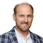 Kunsthandwerk Porträt eines lächelnden Mannes mit kariertem Sakko vor weißem Hintergrund