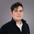 Datenschutz Porträt eines jungen Mannes mit schwarzer Jacke vor grauem Hintergrund