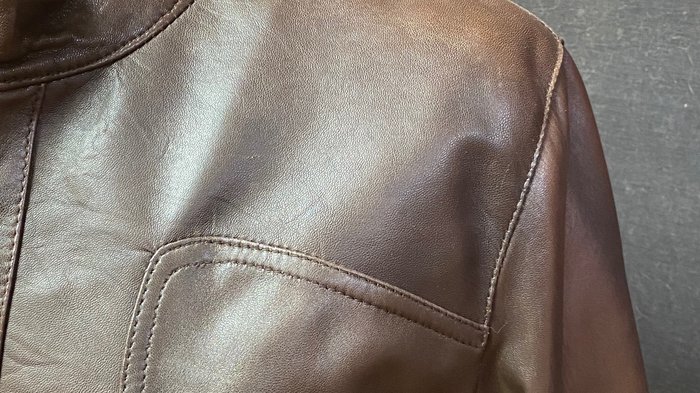 Kürschner Braune Lederjacke mit Reißverschlusstasche und gelbem Stoffhintergrund