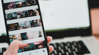 Nachhaltiges Handwerk Hand hält Smartphone mit Fotogalerie vor einem Laptop im Hintergrund