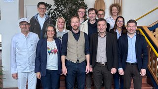 Berufsbildung Gruppenfoto von zwölf Personen in Innenraum vor Treppe und Wanddekoration