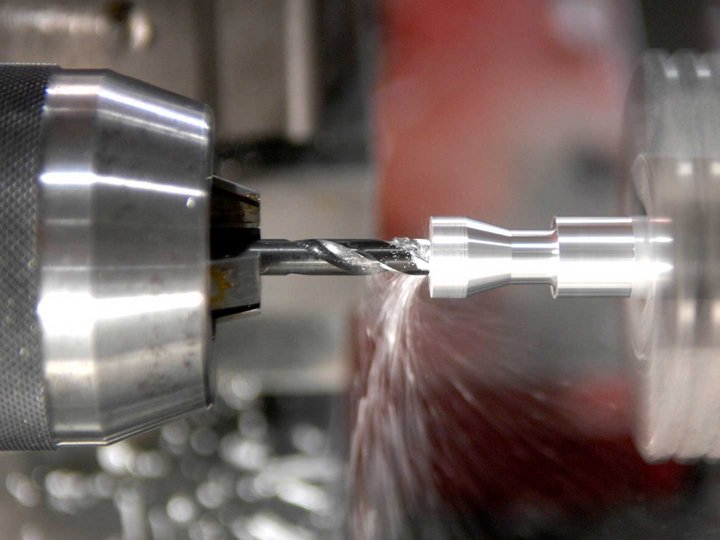 Maschinenbaumechaniker und Werkzeugmacher Drehmaschine bearbeitet Metallteil mit Bohrer in Bewegung