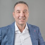 Das lvh-Team Porträt eines lächelnden Mannes in blauem Sakko und weißem Hemd vor grauem Hintergrund