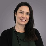 Das lvh-Team Porträt einer lächelnden Frau mit dunklem Haar vor grauem Hintergrund