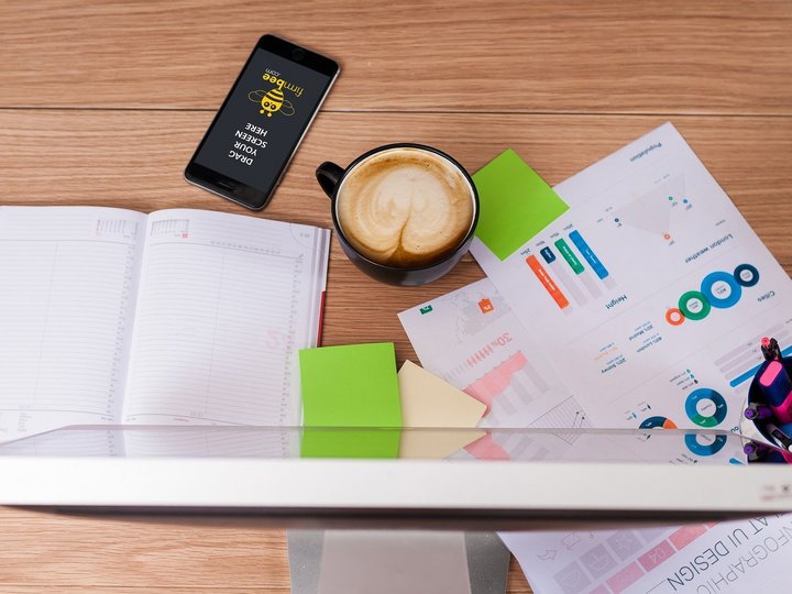 Mediendesigner Arbeitsplatz mit Computer, Smartphone, Kaffee, Notizen und Diagrammen auf Holztisch