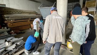 Junghandwerker Gruppe junger Leute in Baustelle mit Betonmischer und Bauholz