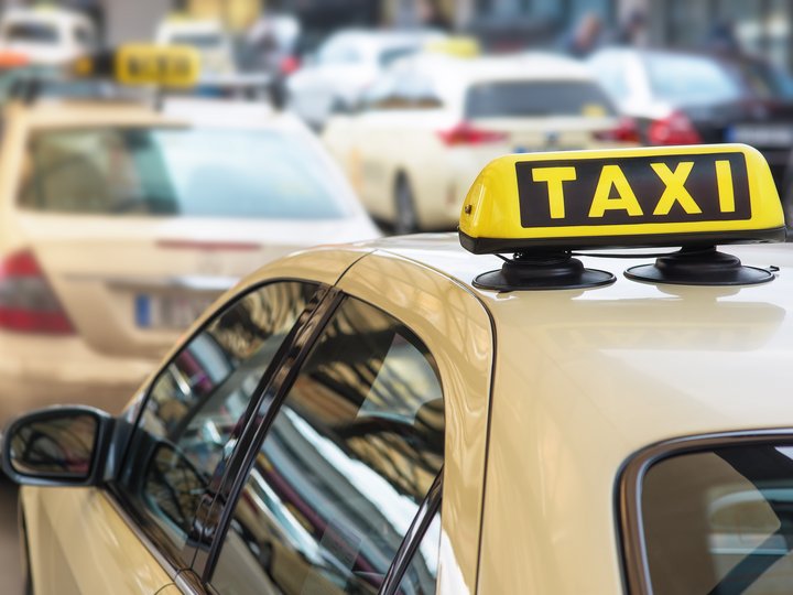 Mietwagen- und Taxiunternehmer Gelbes Taxi mit Taxi-Schild auf dem Dach im Stadtverkehr
