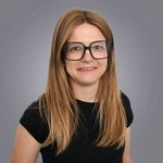 Das lvh-Team Frau mit langen blonden Haaren und schwarzer Brille vor grauem Hintergrund