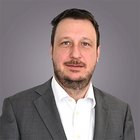 Steuerberatung, Buchhaltung und Lohnabrechnung Porträt eines Mannes in schwarzem Sakko vor grauem Hintergrund