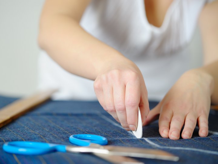 Maßschneider Person markiert Stoff mit Schneidkreide zum Zuschneiden