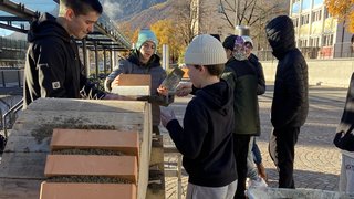 Junghandwerker Jugendliche mauern Ziegelsteine bei sonnigem Herbstwetter im Freien