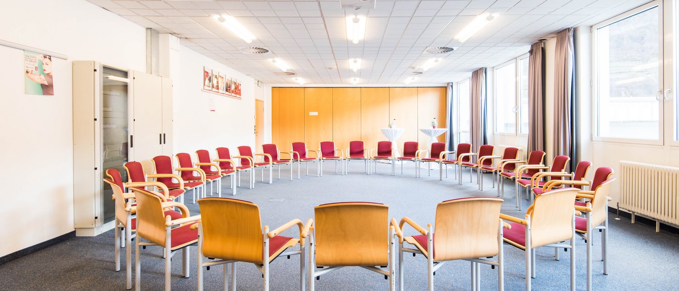 Vermietung Seminarräume Leerer Seminarraum mit Stühlen im Kreis und Projektor an der Decke