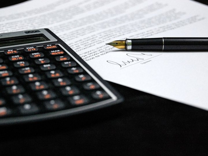 Steuerberatung, Buchhaltung und Lohnabrechnung Taschenrechner und Unterschrift auf einem Vertrag mit Füllfederhalter