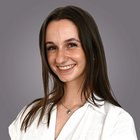 Weiterbildung Lächelnde junge Frau mit braunen Haaren vor grauem Hintergrund