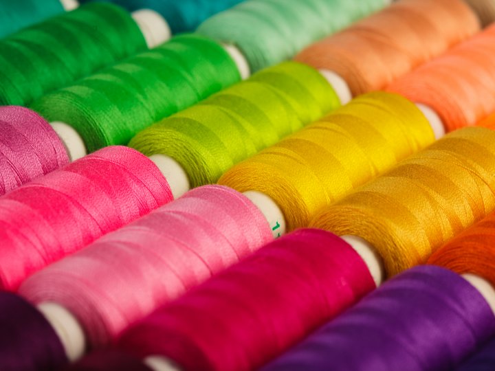 Sticker, Stricker und Weber Bunte Reihen von Garnrollen in verschiedenen Farben