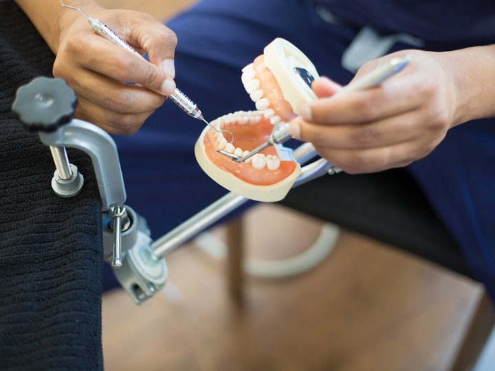 Zahntechniker Zahnarzt übt an Zahnmodell mit Instrumenten