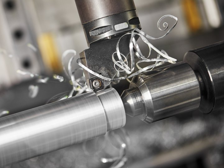 Maschinenbaumechaniker und Werkzeugmacher Metallbearbeitung an einer Drehmaschine mit Metallspänen