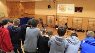 Junghandwerker Junge beobachten Preisverteilung in Turnhalle mit Anzeigetafel und Präsentation