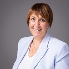 Unfall und Krankheit Porträt einer lächelnden Frau mit kurzem braunem Haar und hellblauem Blazer