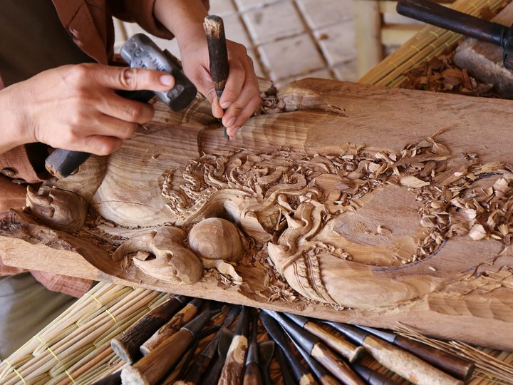 Holzbildhauer Hand schnitzt Holzrelief mit Schnitzwerkzeugen