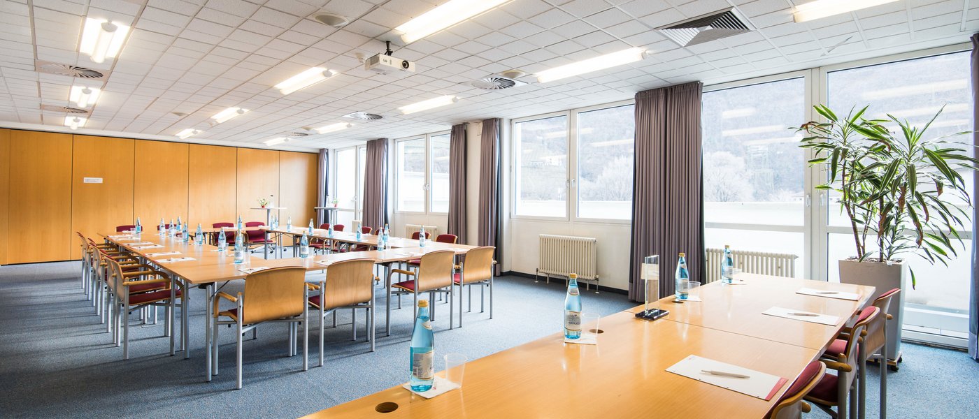 Vermietung Seminarräume Konferenzraum mit Tischen, Stühlen, Wasserflaschen und Schreibblöcken
