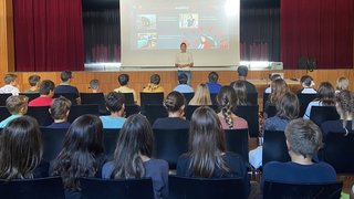Junghandwerker Lehrerin hält Vortrag vor Schülern in Aula über Handwerk und Frauen