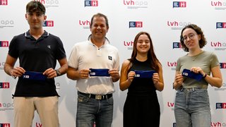 Junghandwerker Vier Personen halten blaue Etuis vor einer lvhapa und Generation H Wand