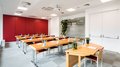Vermietung Seminarräume Heller Schulungsraum mit Holztischen, roten Stühlen und Wasserflaschen