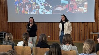 Junghandwerker Zwei Frauen sprechen vor Jugendlichen bei einer Handwerkspräsentation mit Projektorwand