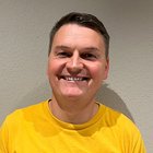 Fliesen-, Platten- und Mosaikleger Lächelnder Mann mit gelbem T-Shirt vor weißer Wand