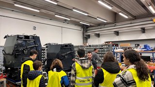 Junghandwerker Gruppe von Besuchern mit gelben Warnwesten bei einer Führung in einer Werkstatt
