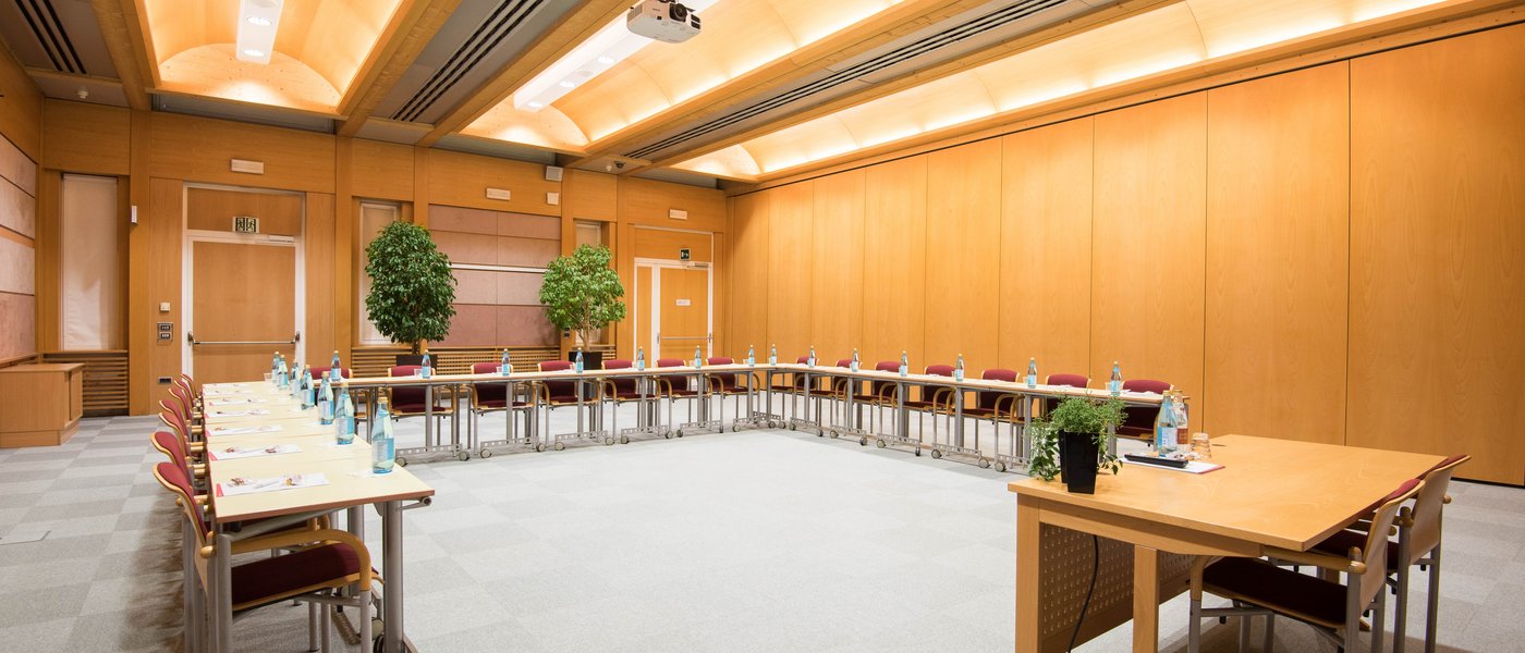 Vermietung Seminarräume Leerer Konferenzraum mit U-förmigen Tischreihen und Stühlen