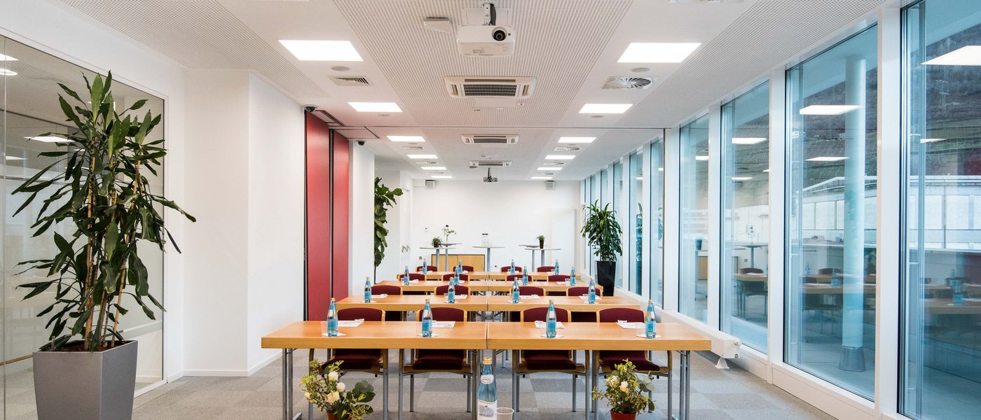 Vermietung Seminarräume Moderner Konferenzraum mit Reihen von Tischen, Stühlen und Wasserflaschen