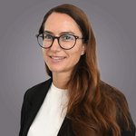 Das lvh-Team Porträt einer Frau mit langen braunen Haaren und Brille vor grauem Hintergrund