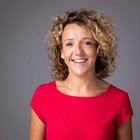 Kernthemen Fröhliche Frau mit lockigem Haar in rotem Kleid vor grauem Hintergrund