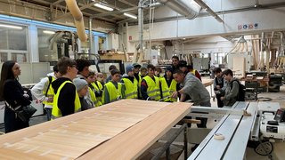 Junghandwerker Gruppe von Kindern in Sicherheitswesten in einer Holzwerkstatt bei einer Führung